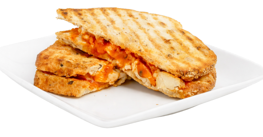 Buffalo chicken Melt - Edited Buffalo Chicken Melt Panini on a plate, featuring grilled chicken, spicy sauce, and toasted bread, highlighting hearty and healthy dining options at Farm2Cup Fairhaven.